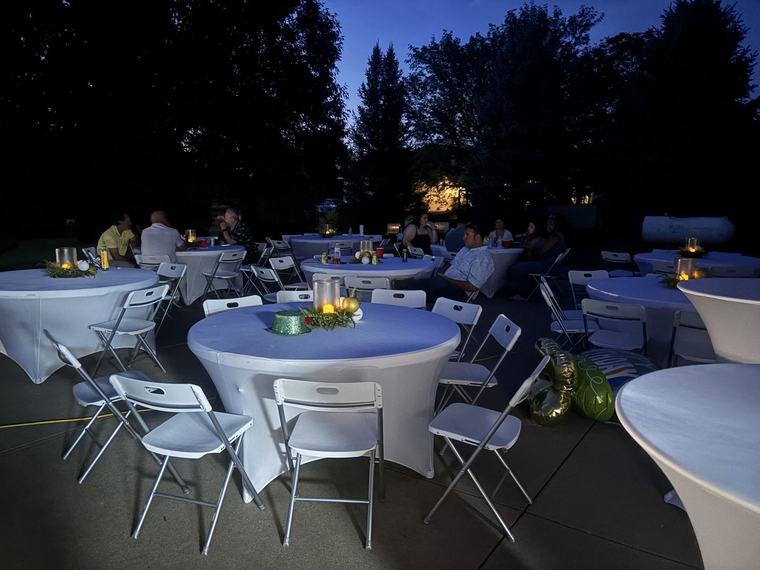 Round tables and chairs set up for a backyard party at dusk