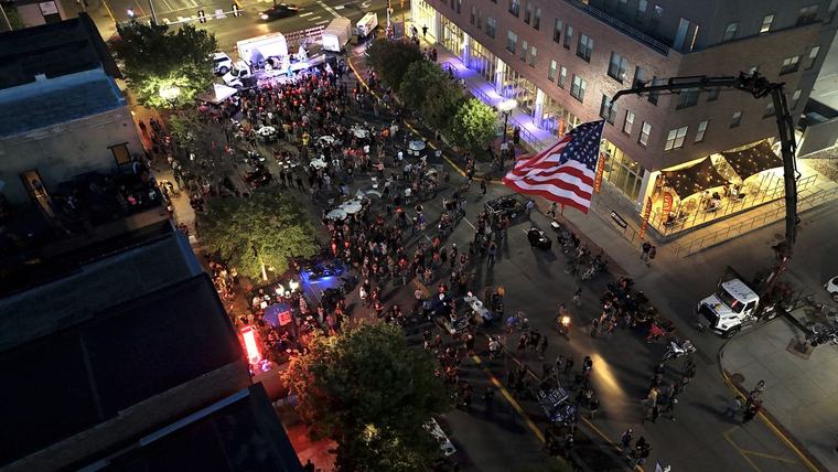 Aerial view of a downtown street party with cocktail tables and a stage