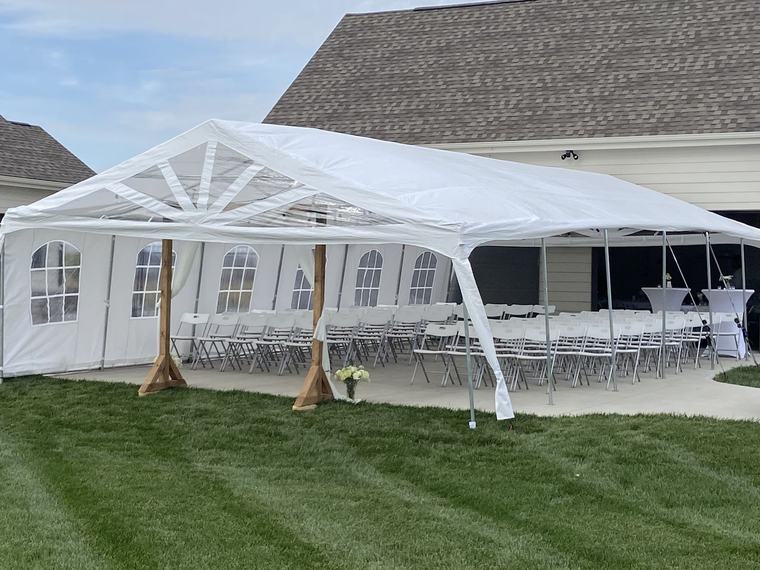 Frame tent with sidewalls and draped posts ready for a wedding ceremony