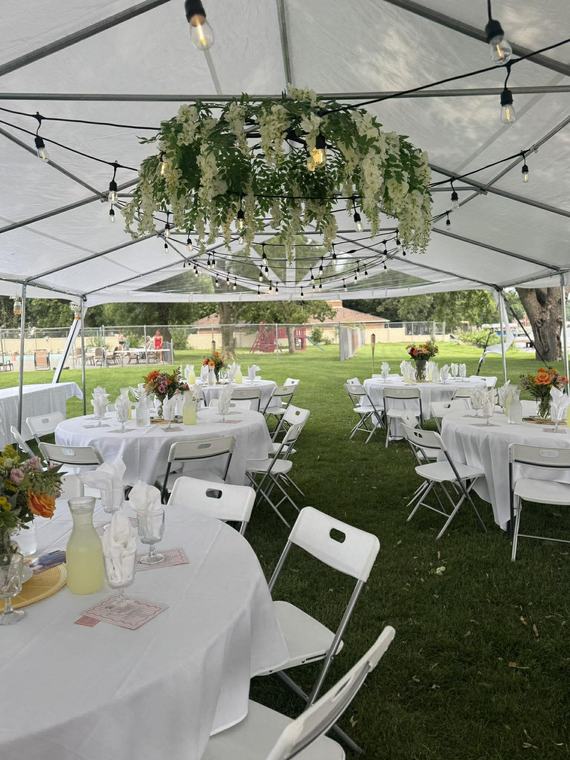Round tables under a tent with a floral chandelier overhead