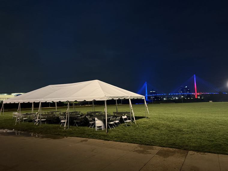 Tent lit up at night with the skyline in the distance