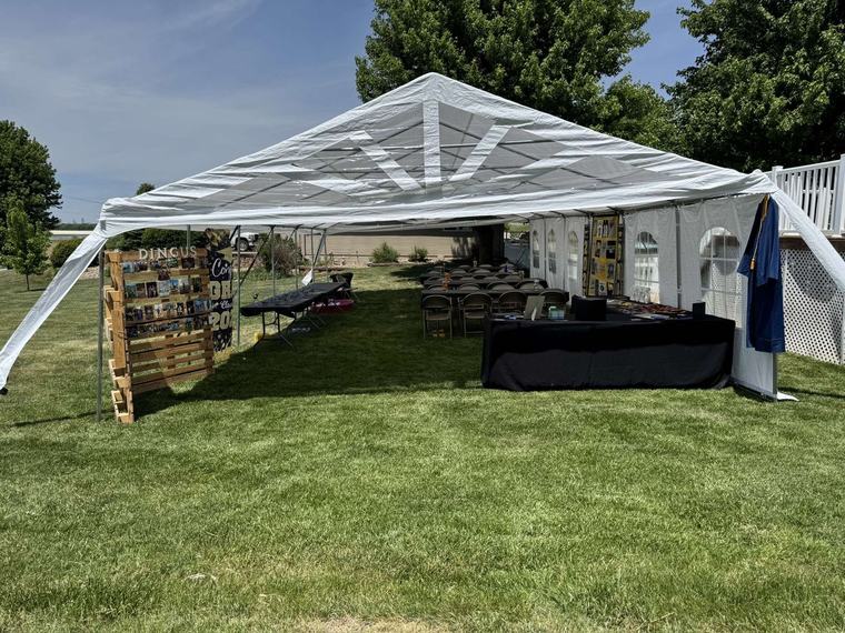 Graduation party under a tent with a photo display and gift table