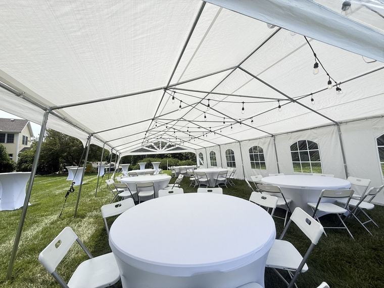 Inside a tent with round tables and warm string lighting