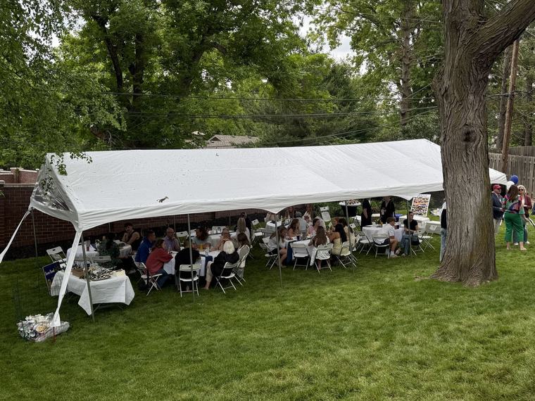 Guests seated under a canopy at a backyard graduation party